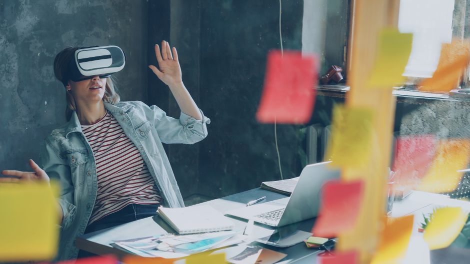 Djelatnica testira VR headset uz bilješke i laptop